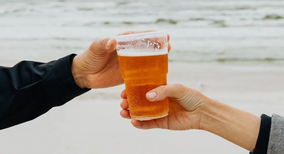 Handshake Over Beer Glass By The Beach